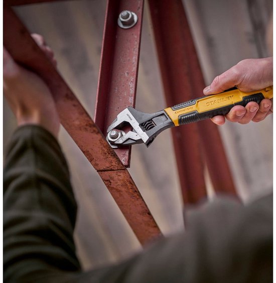 Hand dat een Stanley verstelbare moersleutel gebruikt om een metalen constructie vast te zetten.