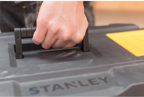 Een hand pakt de zwarte handgreep van een Stanley gereedschapskist.