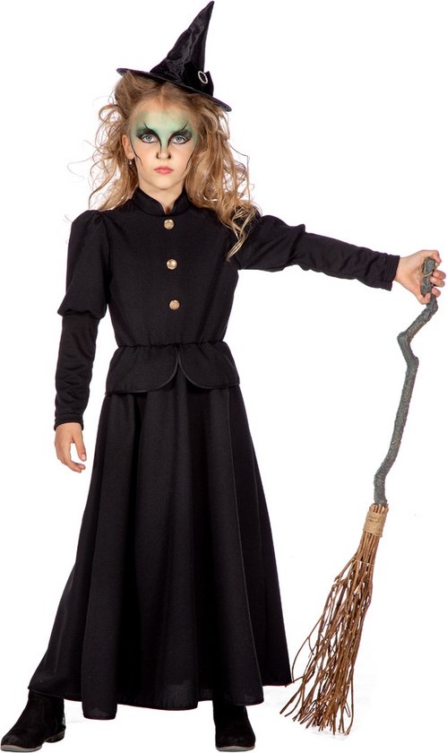 Fille en sorcière avec robe noire, chapeau pointu, manche à balai et maquillage vert.