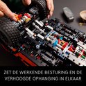 Onderkant van de oranje Mercedes-Benz G 500 modelauto, met zichtbare tandwielen en ophanging. "Zet de werkende besturing en de verhoogde ophanging in elkaar."