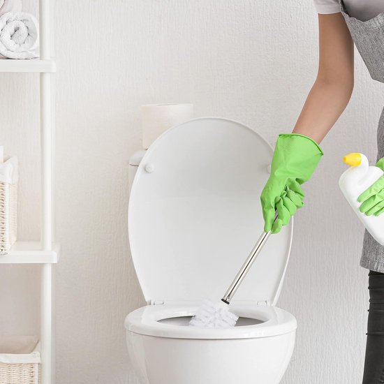 Persoon met groene handschoenen maakt het toilet schoon met een witte toiletborstel met metalen steel.
