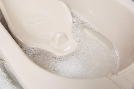 Beige badzitje met schuim in het water.