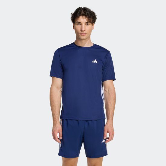 Man in volledig donkerblauw sportpak met witte Adidas logo's en strepen.