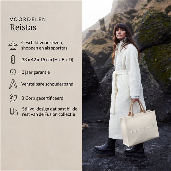 Model met witte SUITSUIT reistas, staand op een rotsachtige kust.