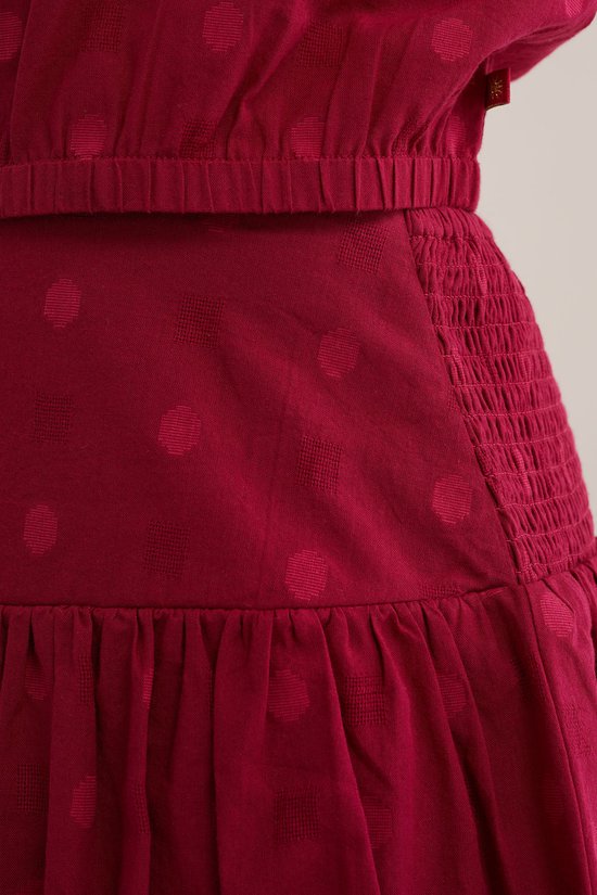 Gedetailleerde close-up van de donkerrode rok met stippenpatroon en elastische taille.