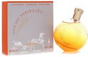 Elixir des Merveilles eau de parfum flacon en doos. De ronde, oranje flacon is bezaaid met gouden glitters. De doos toont een paard en koets.