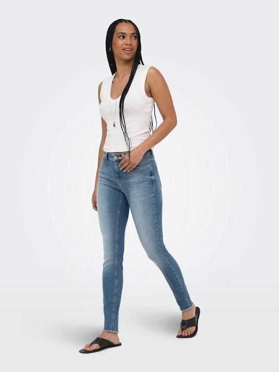 Model in een blauwe skinny fit jeans met middelhoge taille, kijkend naar de zijkant.