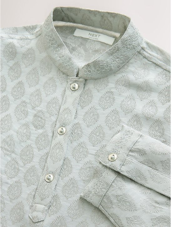 Detailopname van de kraag en knoopsluiting van een lichtgroene kurta met bladpatroon en label 'Next'.