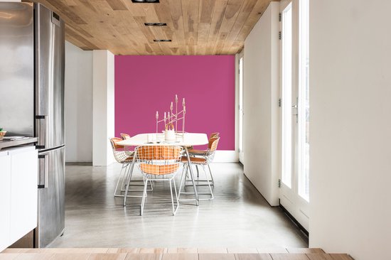 Een eetkamer met een fuchsia muur, witte muren en oranje stoelen.