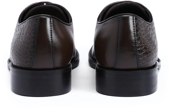 Achterkant van donkerbruine leren schoenen met krokodillenprint en zwarte hakken.