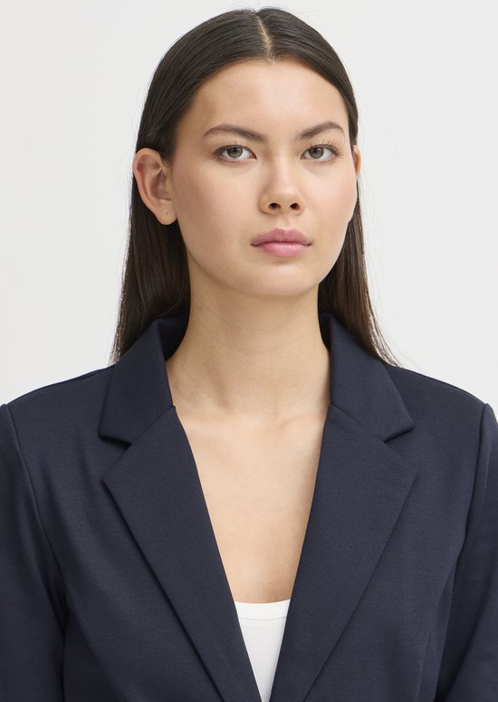 Close-up van een model in een donkerblauwe blazer.