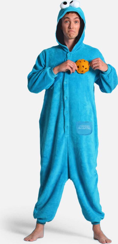 Un homme porte une combinaison bleue Cookie Monster, tenant un biscuit sur sa poitrine. La combinaison a de grands yeux sur la capuche.
