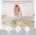 Een blonde vrouw omhelst een lichtgroene Blumtal fleecedeken van 270x230 cm. Gezellig warm, licht en extra zacht.
