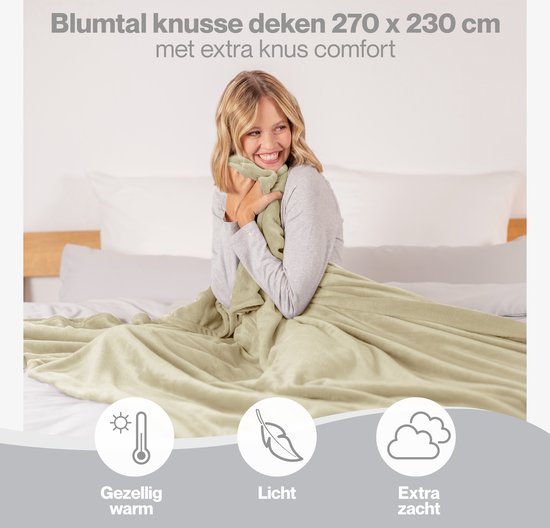 Een blonde vrouw omhelst een lichtgroene Blumtal fleecedeken van 270x230 cm. Gezellig warm, licht en extra zacht.