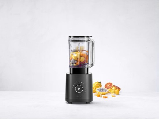 Blender noir sur un comptoir avec des fruits dans le pichet et à côté.