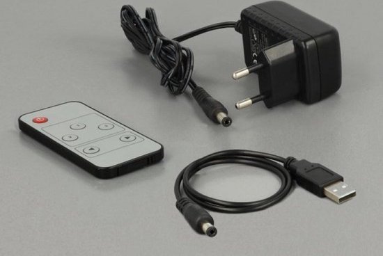 Zwarte afstandsbediening, stroomadapter met Europese stekker en USB-naar-DC-kabel op grijze achtergrond.