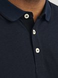 Close-up van de kraag en knoopjes van een donkerblauw poloshirt.