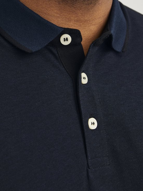 Close-up van de kraag en knoopjes van een donkerblauw poloshirt.