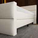 Gedetailleerde kijk op de beige boxspring, met een gestreept hoofdbord en een matras met honingraatpatroon.