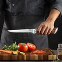 Chef tenant un couteau de cuisine japonais Damas. À côté de tomates et de carottes sur une planche à découper.