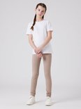 Meisje met een witte T-shirt en taupe legging.