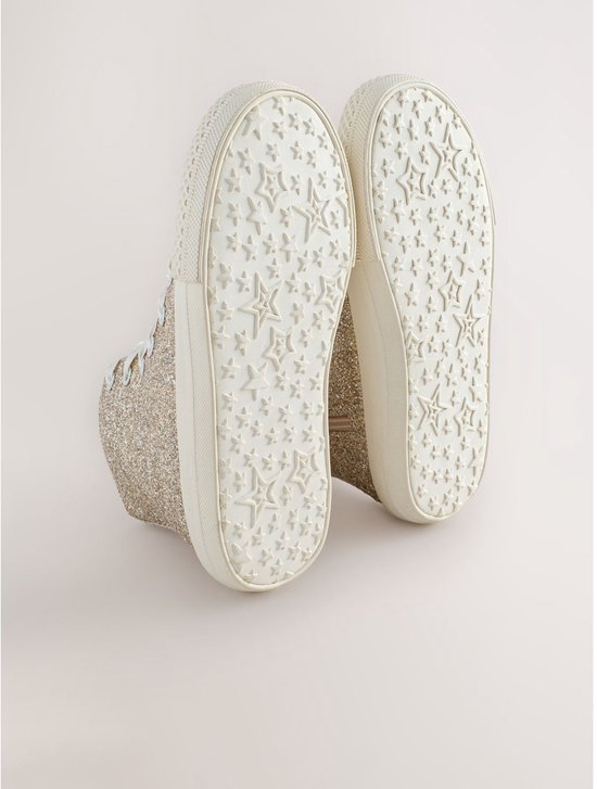 Onderkant van gouden glitter hoge sneakers met witte zolen met sterrenpatroon.