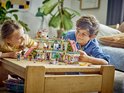 Des enfants jouent avec un set de centre commercial LEGO Friends. Construction blanche, rose et verte avec des personnages et des meubles sur une table.
