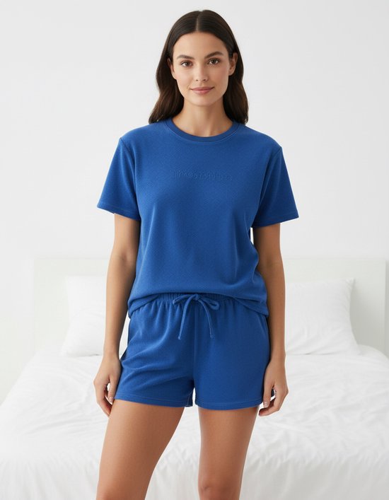 Model in blauwe badstof pyjama: T-shirt met korte mouwen en shorts met trekkoord.