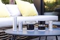 Netatmo Slimme Regenmeter, thermometer en anemometer op een tuintafel met een bank op de achtergrond.