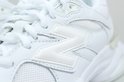 Detail van het witte N-logo op een witte New Balance sneaker.