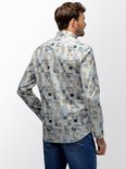 Man draagt een langarmig overhemd met mozaïekprint van beige, blauwe en witte vierkanten, gezien vanaf de achterkant.