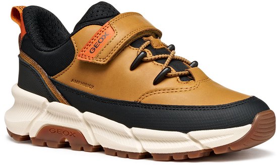 Bruine sneaker met zwarte accenten, oranje lus en klittenbandsluiting.