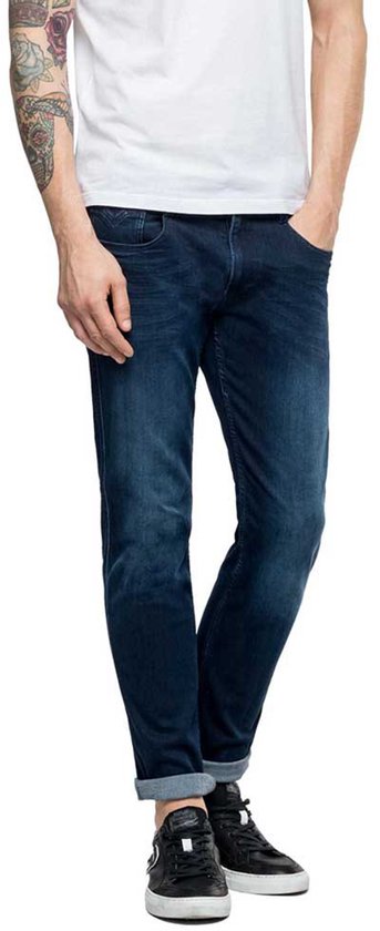 Donkerblauwe Replay jeans met lichte wassing, gedragen door een man met omgeslagen broekspijpen.