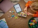Enfant construisant avec un set LEGO Friends sur une table, avec une tablette et des accessoires pour animaux.