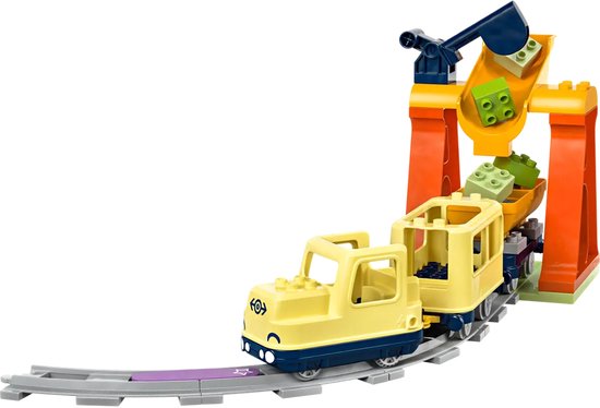 Gele LEGO Duplo trein met wagon, een oranje kraan die blokjes laadt.