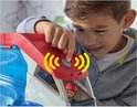 Een jongen drukt op de lanceerknop van de PAW Patrol Patroller, een groot blauw, wit en rood voertuig met transparante deuren.