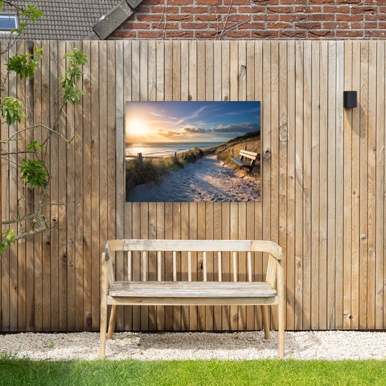 Zonsondergang op een strand met duinen, een zandpad, houten hekken en een bankje. Hangt aan een houten schutting boven een houten bank.