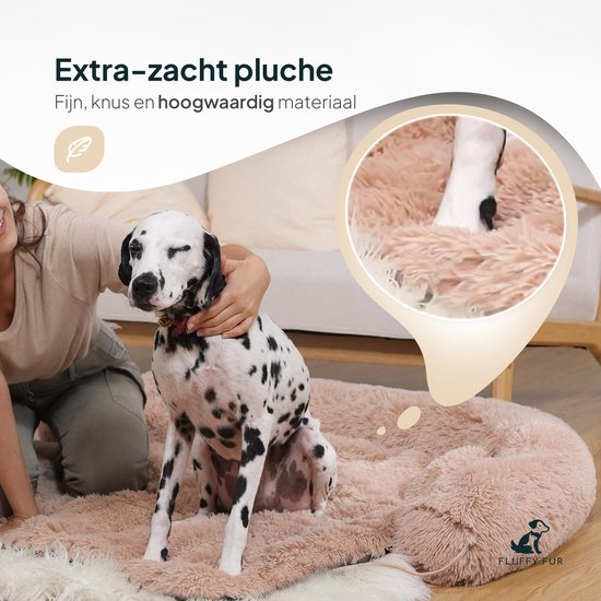 Een Dalmatiër zit op een zachtroze pluche hondenmand, terwijl een vrouw hem aait.