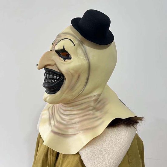 Creatie van 'Art the Clown' masker met opvallende gele huid, grote zwarte mond, tanden, oogmake-up en een zwarte hoed.