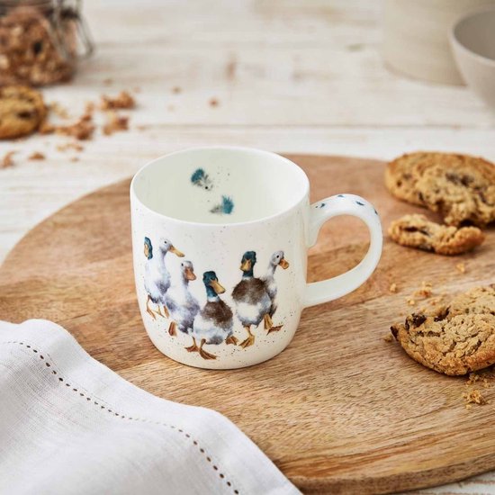 Witte mok met aquarelprint van zes eenden op een houten plank met koekjes en een servet.