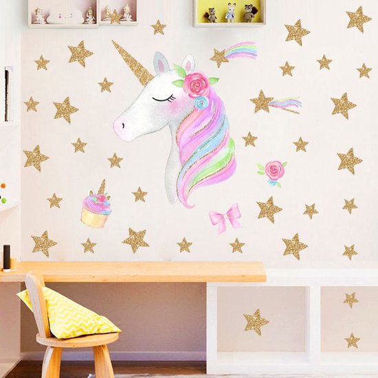 Étoiles dorées pailletées et sticker mural licorne dans une chambre d'enfant au-dessus d'un bureau.