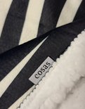 Label met 'cosas' op een zachte witte fleece stof, naast een zwart-wit gestreepte stof.