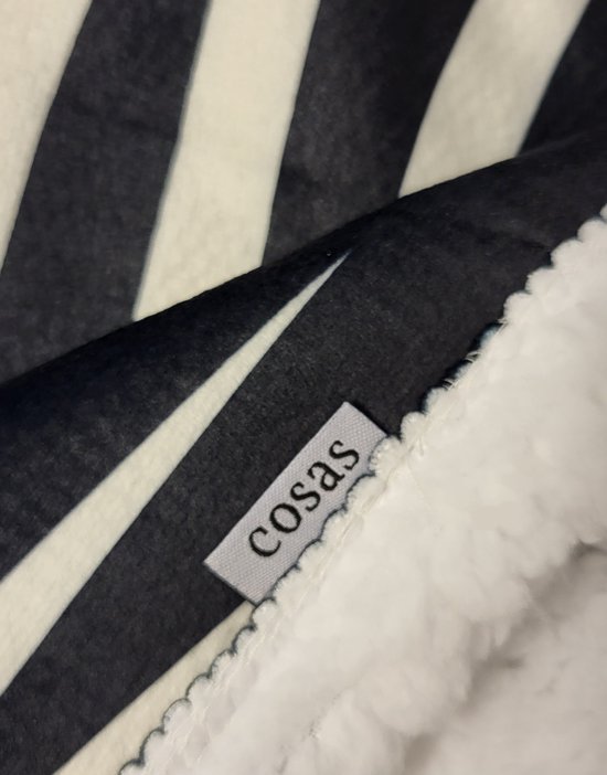 Label met 'cosas' op een zachte witte fleece stof, naast een zwart-wit gestreepte stof.