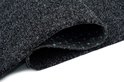 Tapis gris foncé enroulé avec texture visible et picots verts.