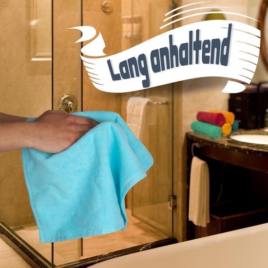Een hand houdt een lichtblauwe handdoek vast. Op de achtergrond in een badkamer, een stapel handdoeken in oranje, groen en rood.