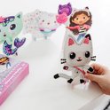 Wit kattenfiguur met strass-steentjes, vastgehouden door handen, met andere figuren op de achtergrond.
