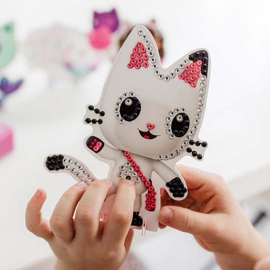 Wit kattenfiguur met strass-steentjes in roze en zwart, en een roze ketting.