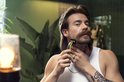 Man met lang haar, snor en witte tanktop trimt zijn nek met een groene en zwarte Philips OneBlade.