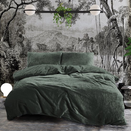Een opgemaakt bed met donkergroen teddypluche dekbedovertrek en kussenslopen, in een slaapkamer met behang.