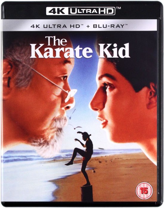 De voorkant van de 4K Ultra HD Blu-ray-hoes van The Karate Kid met Mr. Miyagi en Daniel LaRusso die naar een kleine vechtende figuur kijken.